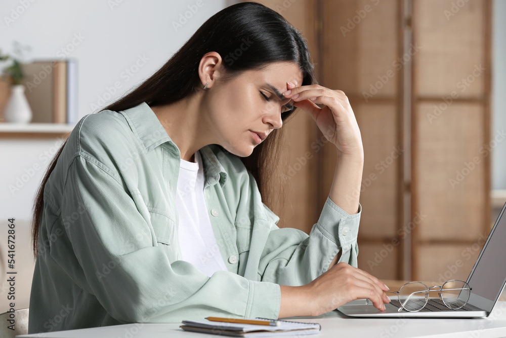 Young woman suffering from eyestrain at desk in office Young woman suffering from eyestrain at desk in office