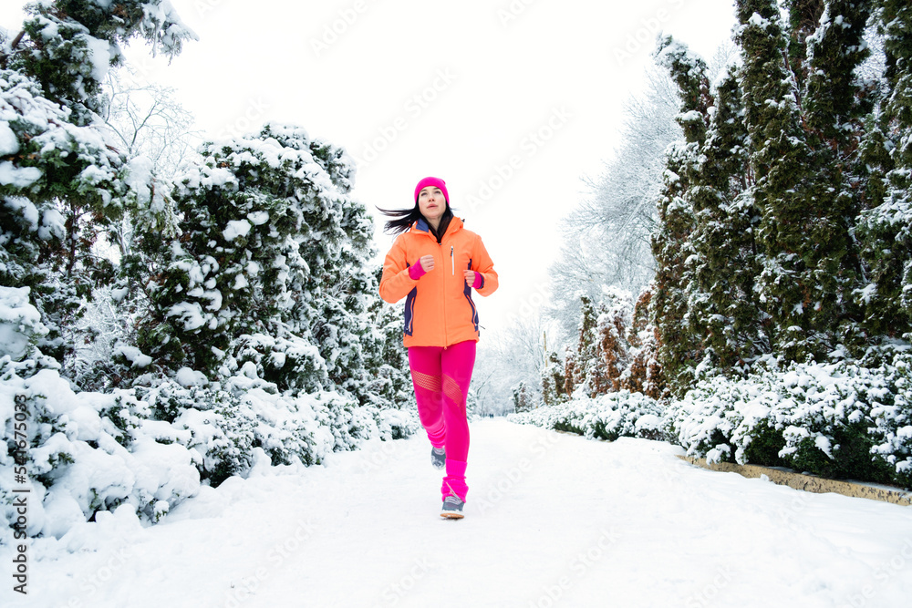 Gear Up for Cold Weather Running, How to Dress for Winter Running. Running woman in sportswear jogging in winter park. Fitness woman running during winter workout.