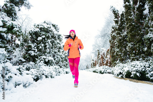 Gear Up for Cold Weather Running, How to Dress for Winter Running. Running woman in sportswear jogging in winter park. Fitness woman running during winter workout.