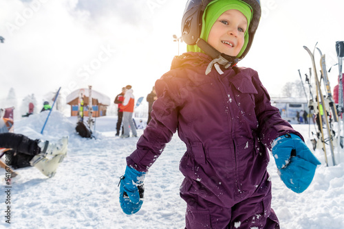 Fotografie Cute adorable little kid boy enjoy having fun sledging down hill of snow heap snowdrift at alpine mountain skiing resort on bright winter day