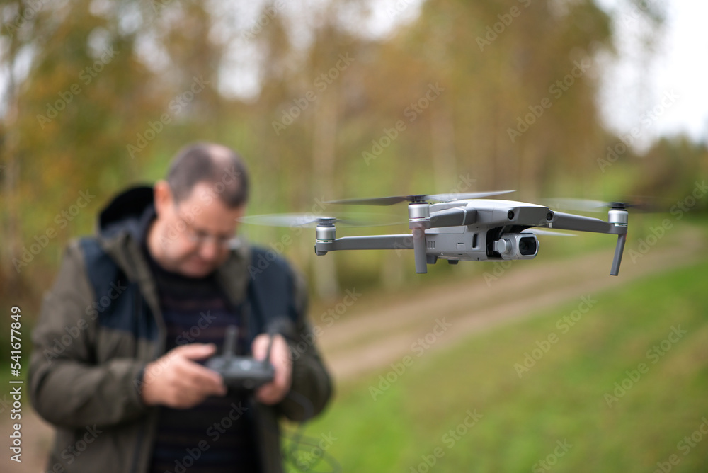 Mature man operating drone flying or hovering by remote control in nature Mature man operating drone flying or hovering by remote control in nature