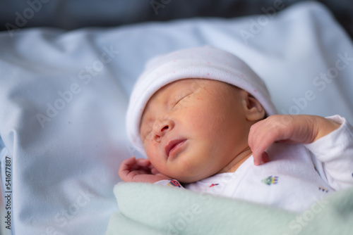 Close up portrait of adorable little newborn baby girl lying quiet at hospital crib hours after coming to life
