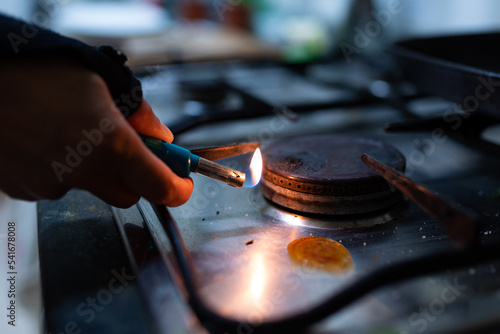 A hand is seen holding a lighter while turning on the gas burner of a kitchen stove. Due to Russia's invasion of Ukraine gas prices have reached record highs in 2022