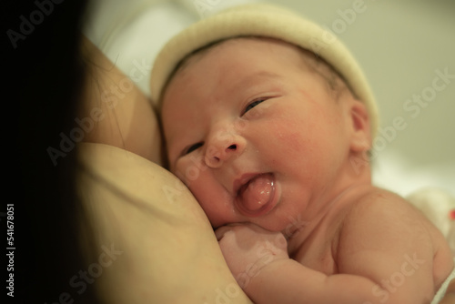lifestyle shot of woman holding adorable newborn baby girl skin on skin  immediately after birth laying happy on hospital bed in new life and parenting concept