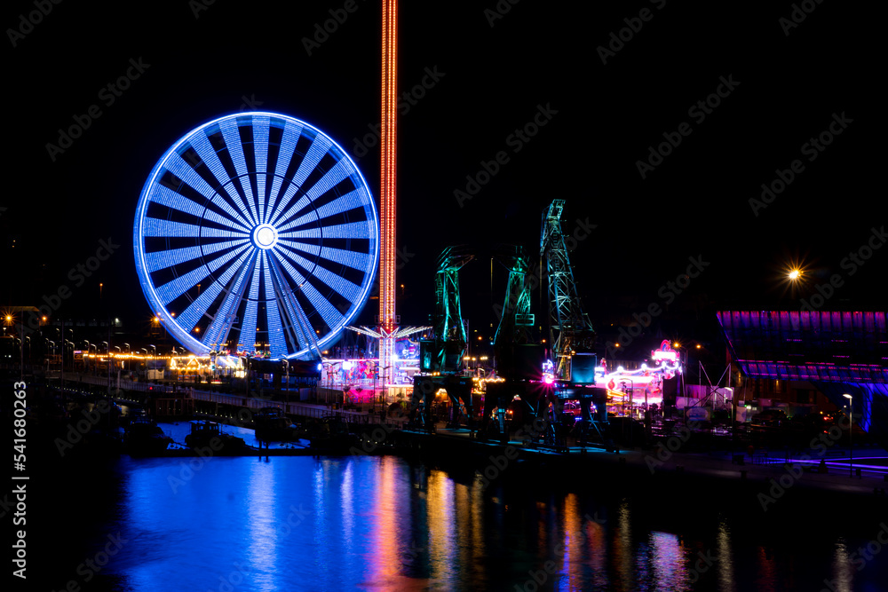 Colorful Szczecin by the river Oder at night.
City at night and neon lights, ferris wheel and bridge.
Poland, summer 2022
