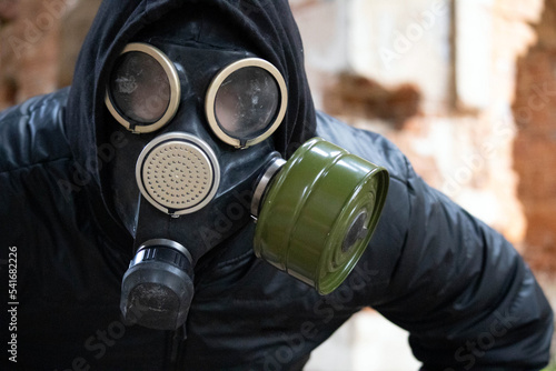 Close-up of a man in a gas mask looking straight ahead. Photo of a guy in black clothes