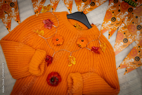 Orange sweater with pumpkins and a garland. © Nataliya