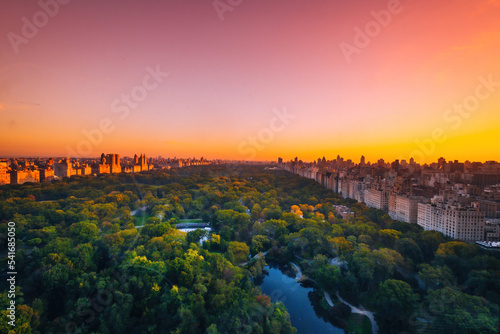 Aerial view of the Central park in Manhattan, New York with golf fields and tall skyscrapers surrounding the park. Sunset view.