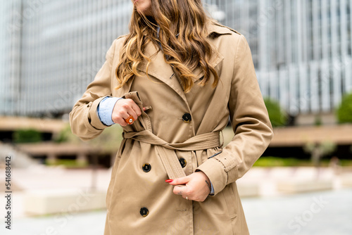 Canvas Print Cutout of executive woman buttoning her trench coat outdoors