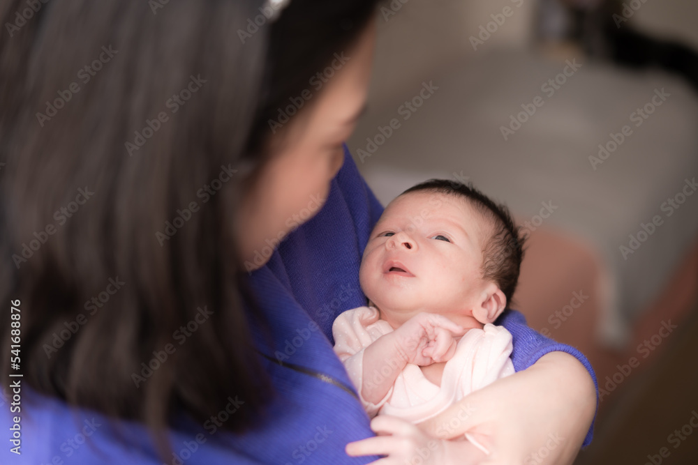 lifestyle shot on young and happy Asian Chinese woman holding tenderly her adorable newborn baby girl in her arms in mother and daughter love and care concept lifestyle shot on young and happy Asian Chinese woman holding tenderly her adorable newborn baby girl in her arms in mother and daughter love and care concept