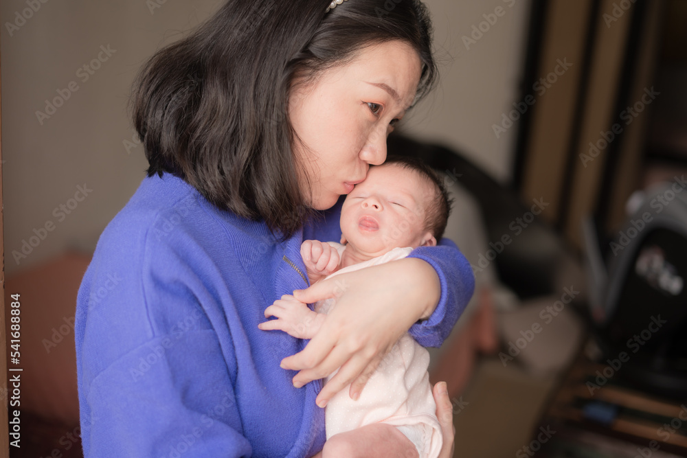 lifestyle shot on young and happy Asian Chinese woman holding tenderly her adorable newborn baby girl in her arms in mother and daughter love and care concept lifestyle shot on young and happy Asian Chinese woman holding tenderly her adorable newborn baby girl in her arms in mother and daughter love and care concept