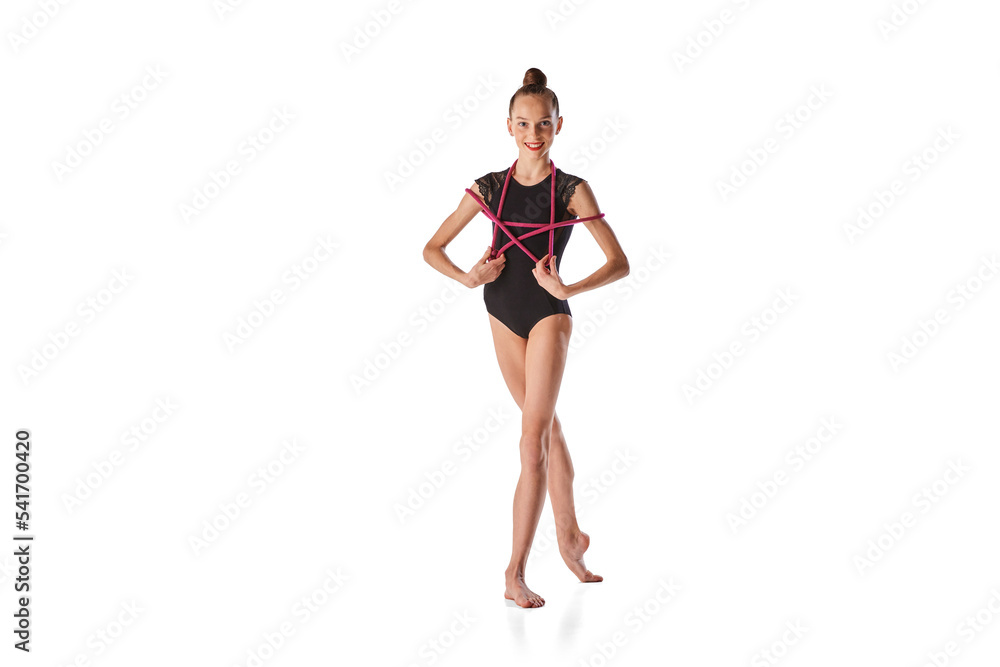 Art in motion. Portrait of junior gymnast in black sport swimsuit doing gymnastics excercises isolated over white background. Sport, skills, achievements Art in motion. Portrait of junior gymnast in black sport swimsuit doing gymnastics excercises isolated over white background. Sport, skills, achievements
