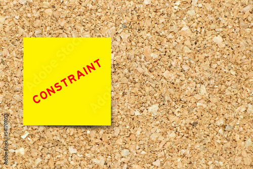 Yellow note paper with word constraint on cork board background with copy space