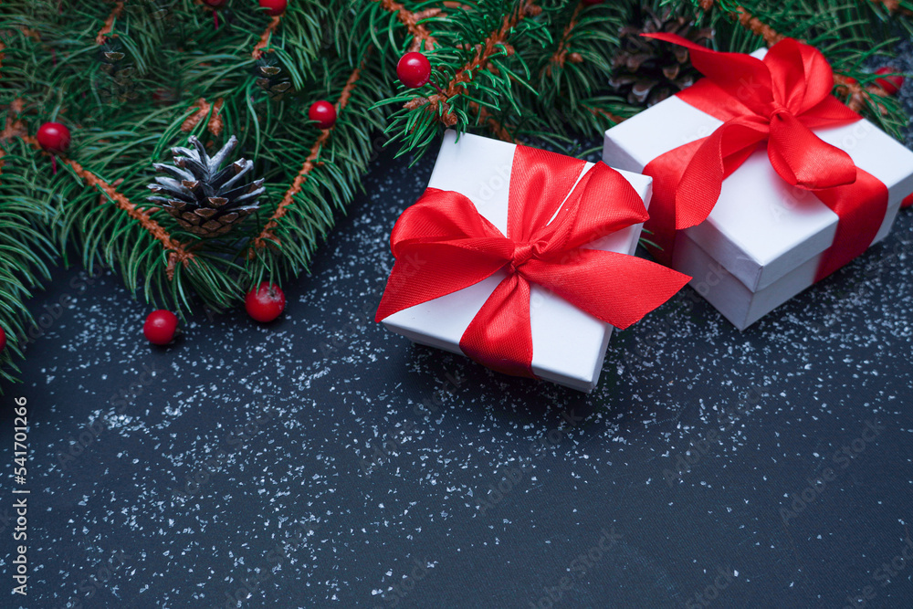 Spruce, fir branches, red berries, gift box on black stone background. Frame border. Christmas New Year composition background. Christmas lights. Space for text Spruce, fir branches, red berries, gift box on black stone background. Frame border. Christmas New Year composition background. Christmas lights. Space for text