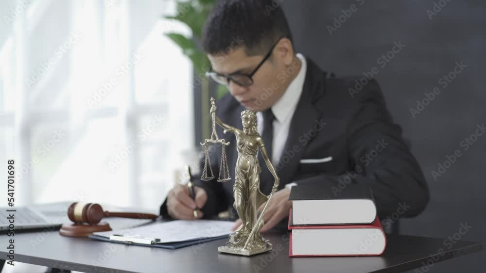 Asian male lawyer working with hammer laptop Goddess of justice in law office, online consulting concept. Asian male lawyer working with hammer laptop Goddess of justice in law office, online consulting concept.