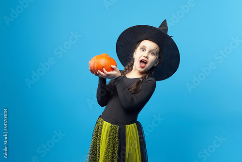 portrait of a charming little girl in a witch costume, Jack's lamps are standing around. the concept of the heluin holiday photo