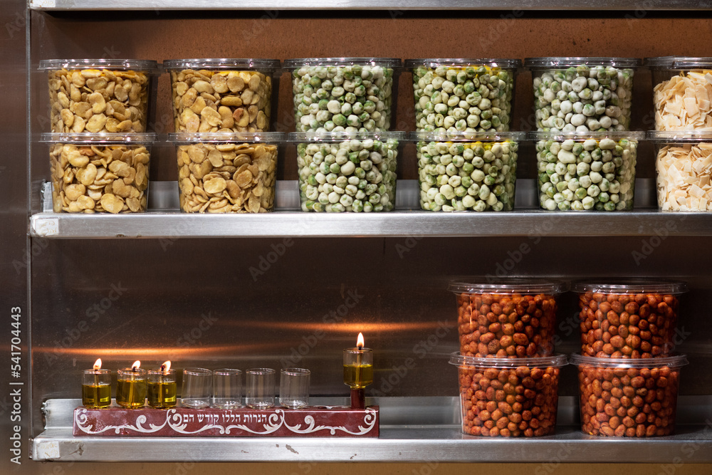 A Hanukkah menorah burns in a store selling dried grains and legumes in the Machane Yehuda market in Jerusalem during the celebration of the Festival of Lights in Israel. A Hanukkah menorah burns in a store selling dried grains and legumes in the Machane Yehuda market in Jerusalem during the celebration of the Festival of Lights in Israel.