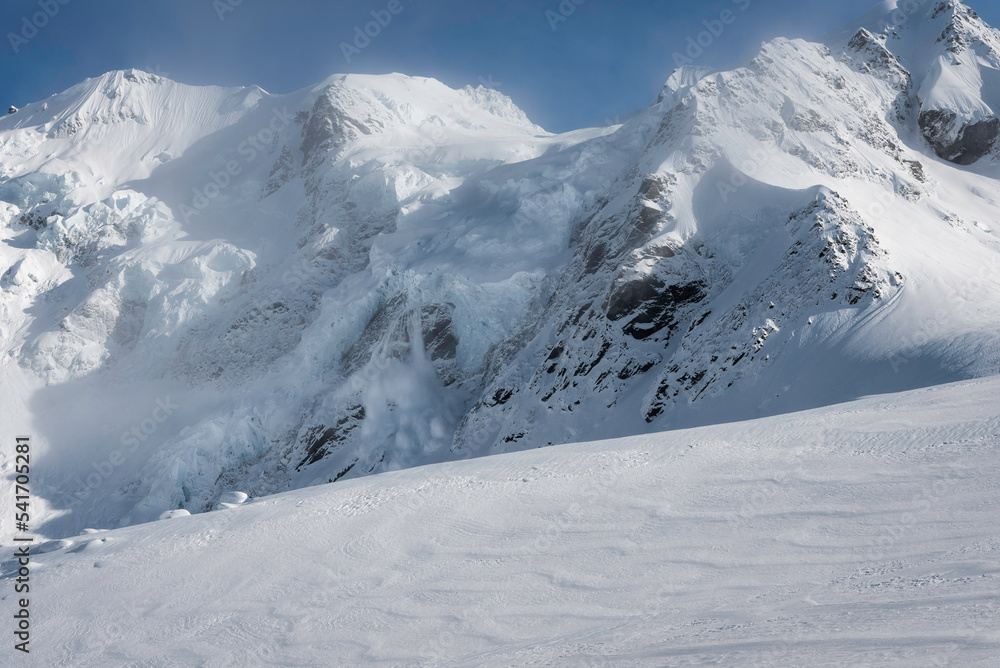 Fototapeta premium An avalanche tumbles off of a calving glacier high in the Southern Alps on top of the Tasman Glacier.