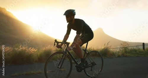 Fitness, man and cycling on road in mountain sports, exercise or workout during sunset in nature. Active male riding bicycle in the mountains for healthy cardio, training or outdoor cycle tour photo