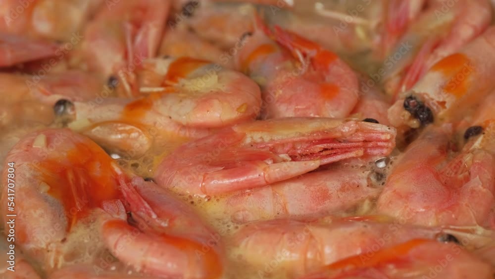 Shrimps preparation. Cooking large shrimp in a shell in frying pan close-up. Tiger prawns in a hot kitchen pan. The cook turns over with a wooden spatula. Roasted shrimps with herbs Shrimps preparation. Cooking large shrimp in a shell in frying pan close-up. Tiger prawns in a hot kitchen pan. The cook turns over with a wooden spatula. Roasted shrimps with herbs