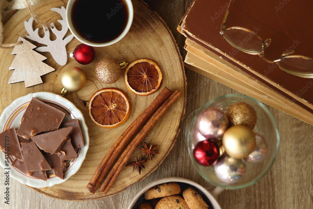 Cup of tea or coffee, various sweets and spices, Christmas decorations, comfy blanket, books and glasses. Top view.