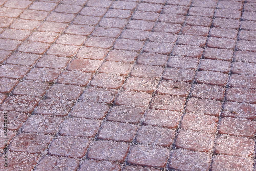 Rock salt on paving slabs in winter. Sprinkled salt on icy sidewalk