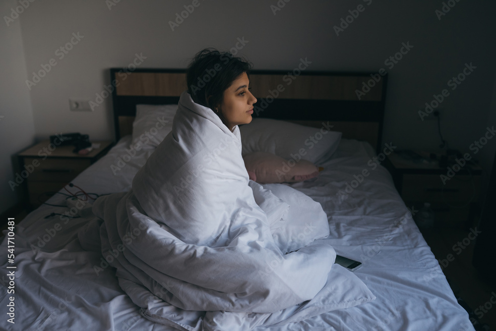 Young woman wrapped in a blanket staring into the distance Stock Photo ...