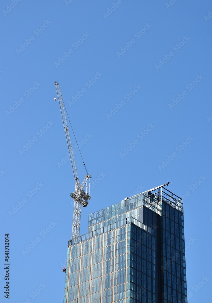 Modern buildings under construction with large cranes and machinery. Modern buildings under construction with large cranes and machinery.