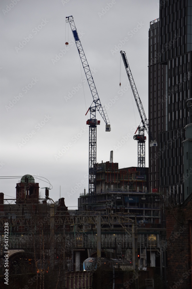 Modern buildings under construction with large cranes and machinery. 