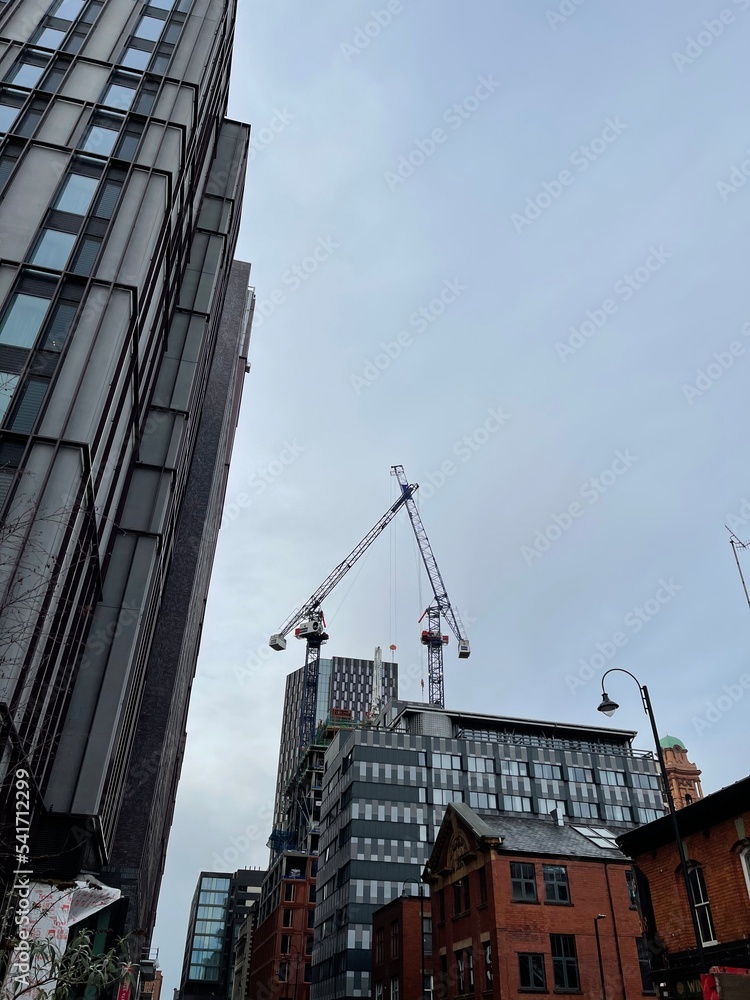 Fototapeta premium Modern buildings under construction with large cranes and machinery. 