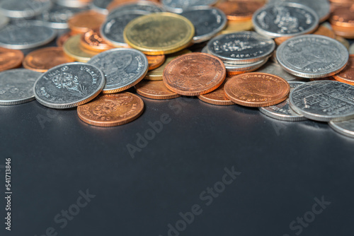 Heap coins on black table with space.