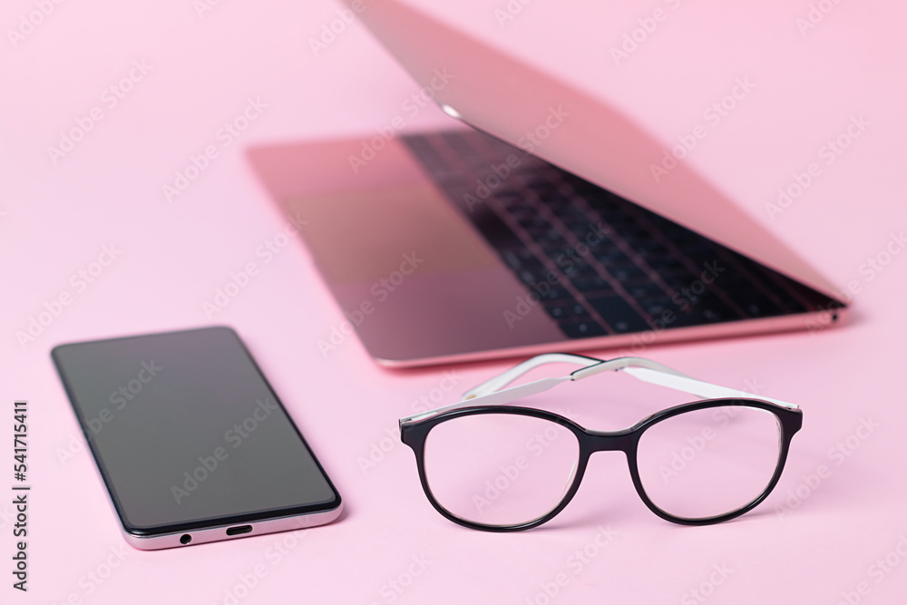 Close-up of eyeglasses, laptop and smartphone on pink background, poor vision concept Close-up of eyeglasses, laptop and smartphone on pink background, poor vision concept