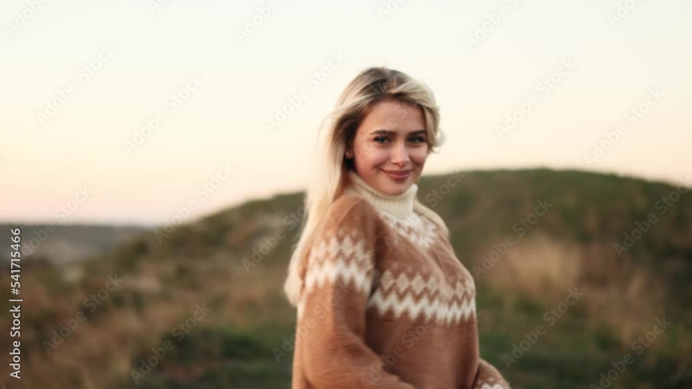 Attractive blond woman walking in the mountains, turns around with flying hair and looking at the camera. Happy relaxed lady walking with beautiful sunset enjoying. Attractive blond woman walking in the mountains, turns around with flying hair and looking at the camera. Happy relaxed lady walking with beautiful sunset enjoying.