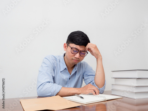 Asian businessman wear glasses sit at working table feels tried