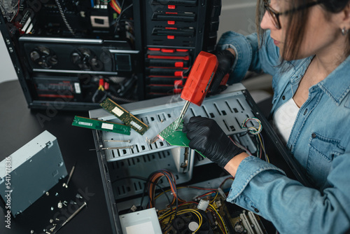 Woman soldering desktop computer with desoldering gun photo
