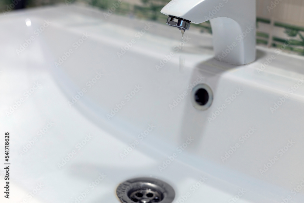 running clean water flows from a tap into a white sink. plumbing running clean water flows from a tap into a white sink. plumbing