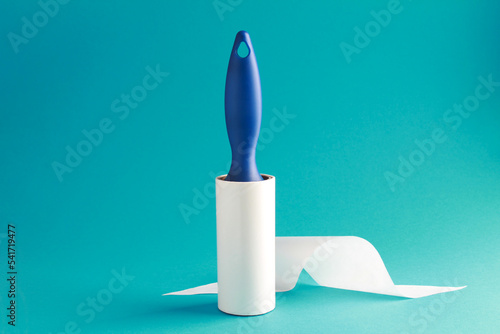 Cloth fabrics cleaner lint roller brush with paper roll blue grip on mint green blue color background. sticky roller, pet cat dog fur dust hair remover