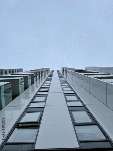 Looking up at modern buildings with a cloudy sky background. 