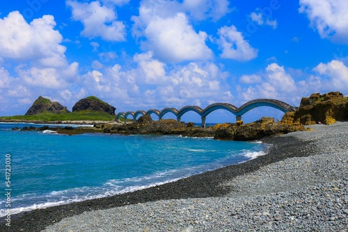 Lovely view of the Sanxiantai nature preserve in Taiwan with a bright blue sea under a cloudy sky photo