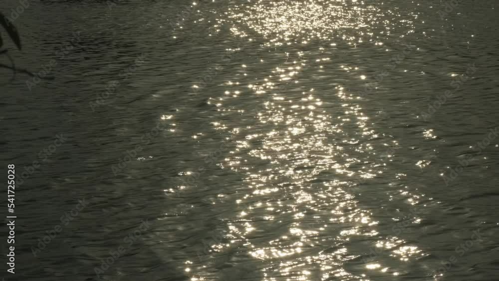 Sun reflections on water at sunset or sunrise. Golden sunlight twinkling and reflecting on water flow of river Sun reflections on water at sunset or sunrise. Golden sunlight twinkling and reflecting on water flow of river