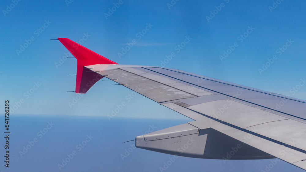 Fototapeta premium Wing of an airplane flying above clouds. Wing of an airplane. view from the window of an airplane flying.