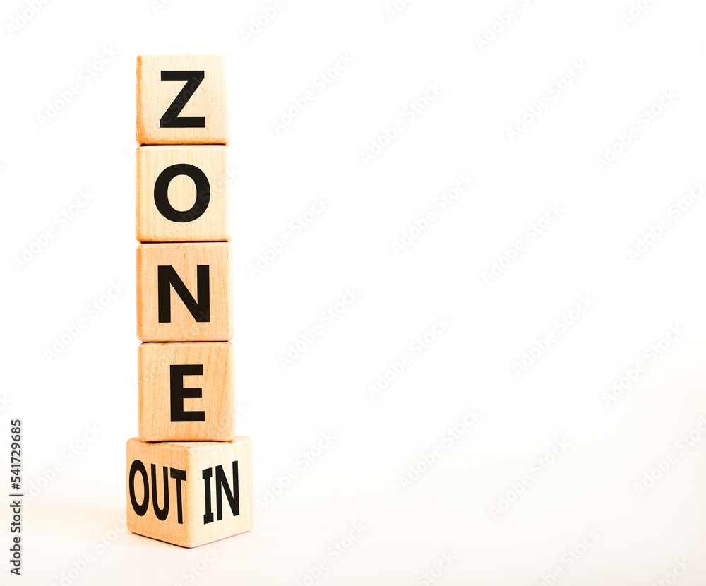 Zone in or out symbol. Concept words Zone in and Zone out on wooden cubes. Beautiful white table white background. Business zone in or out concept. Copy space. Zone in or out symbol. Concept words Zone in and Zone out on wooden cubes. Beautiful white table white background. Business zone in or out concept. Copy space.
