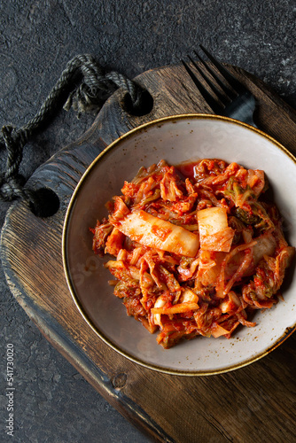 bowl with traditional korean fermented spicy cabbage kimchi on dark table