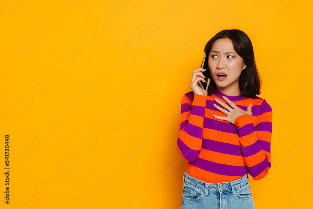 Asian young woman talking on cellphone and expressing frustration Asian young woman talking on cellphone and expressing frustration