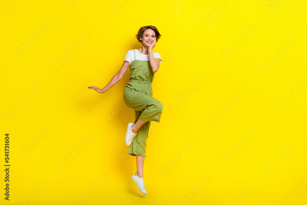 Full length size photo of young stylish girl brown hair touch cheeks carefree weekend jump air relax nice outfit isolated on yellow color background