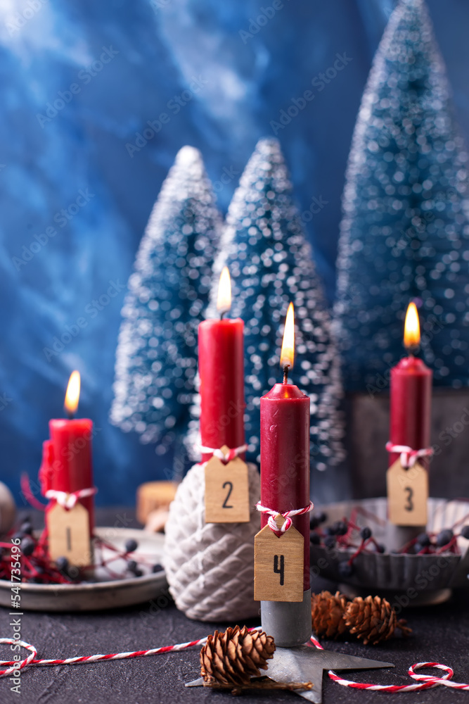 Lovely red and blue advent  Christmas composition. Red burning candles,  wild blue berries and blue decorative trees against blue  textured background. Scandinavian minimalistic style. Still life - obrazy, fototapety, plakaty 