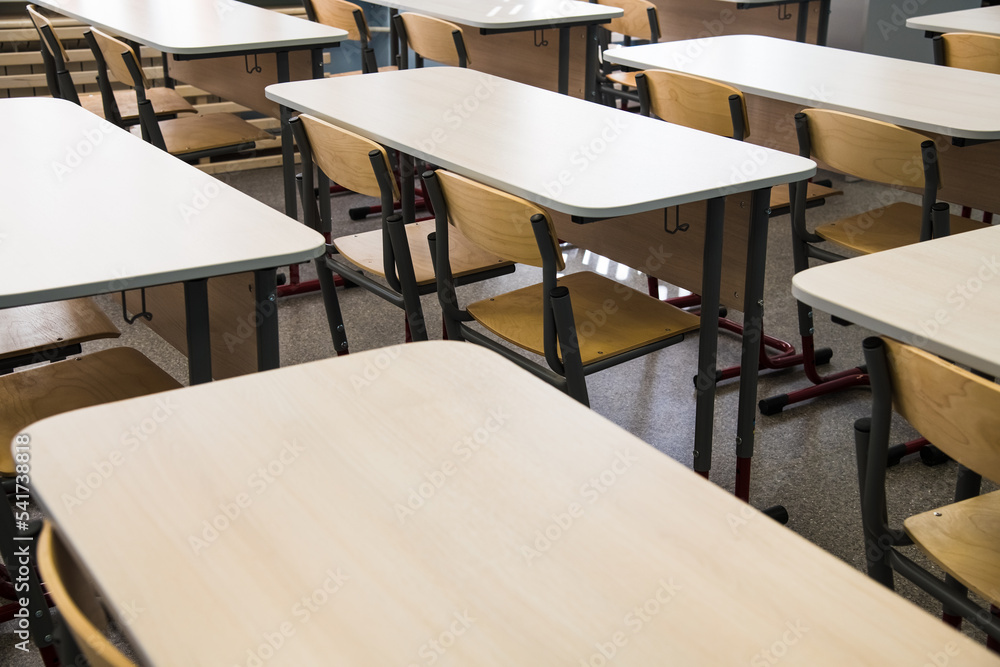 School desks in a row facing the blackboard in an empty classroom Stock