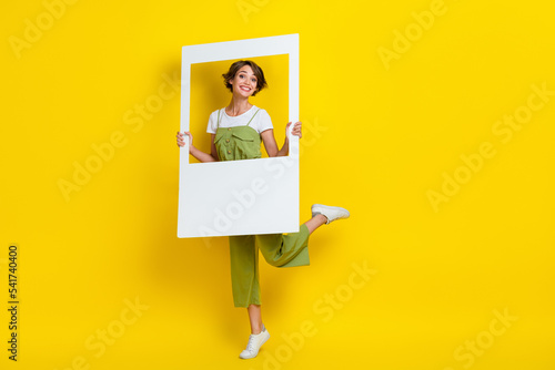 Full size cadre of young funny attractive cute popular blogger lady holding paper window showing satisfied face isolated on yellow color background
