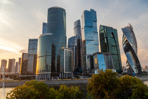 Beautiful high skyscrapers on the banks of the river. Sunset. Tall towers of glass and concrete. Beautiful city buildings. © Kooper