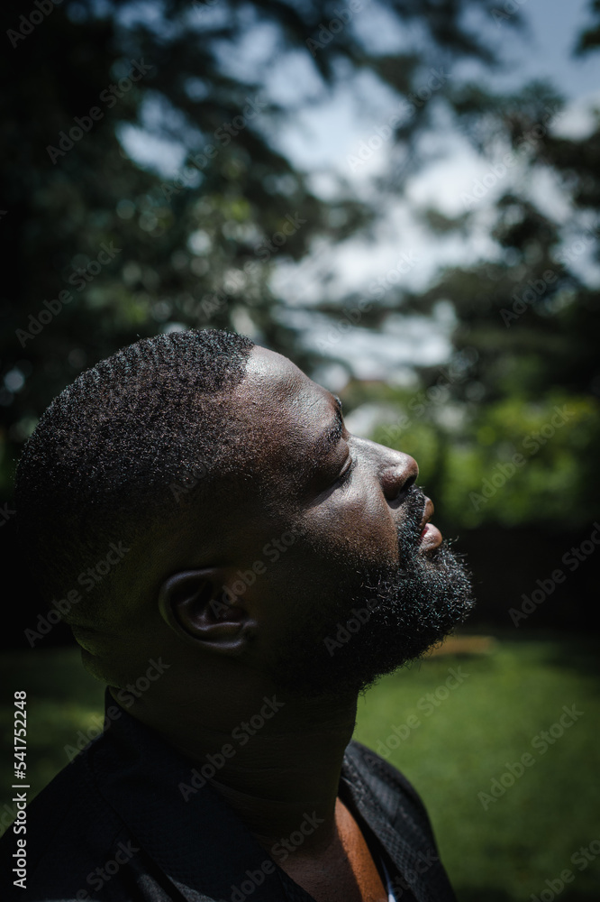A black man basking in the sun in a garden A black man basking in the sun in a garden